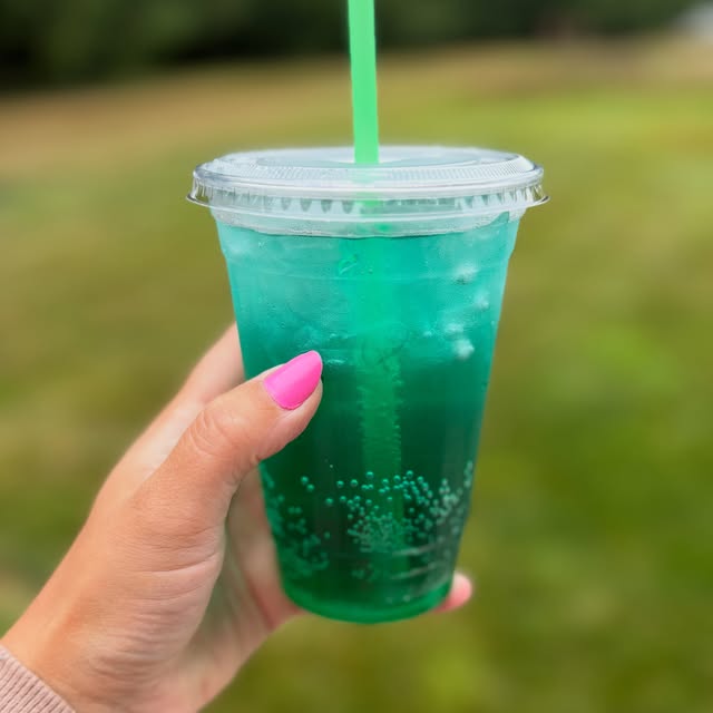 Green Lotus energy drink held up in front of the stand